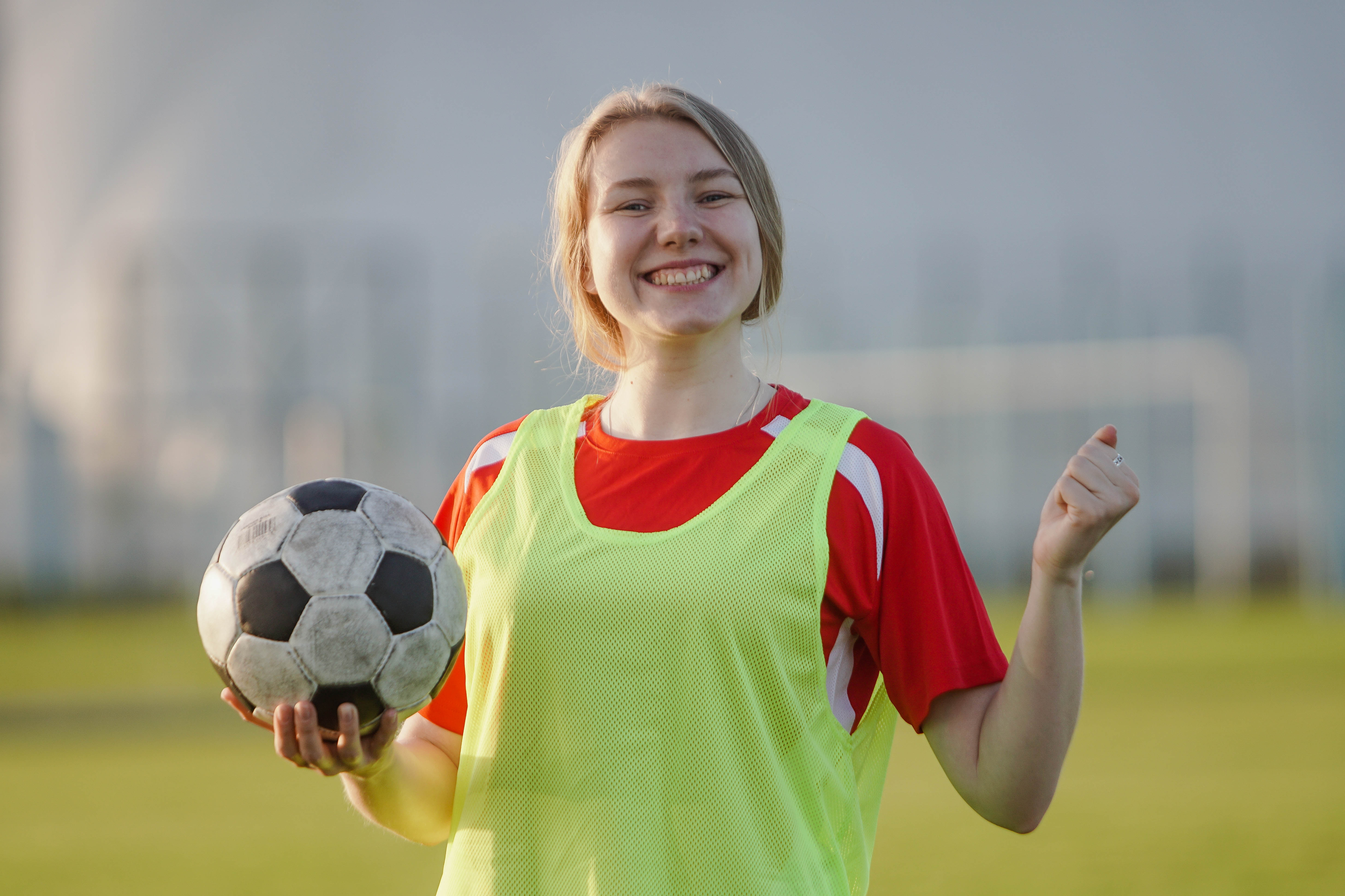 A school age girl smiling and holding a football