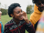 Two young women talking to their friends in a public park.
