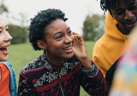 Two young women talking to their friends in a public park.