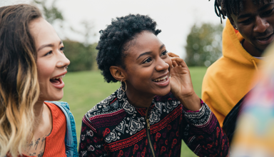 Two young women talking to their friends in a public park.