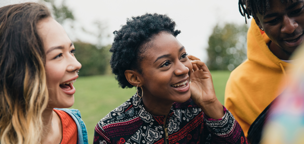 Two young women talking to their friends in a public park.