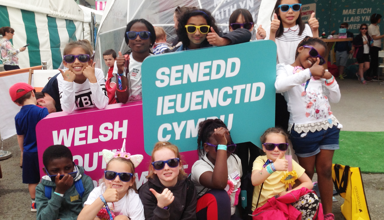 Children holding up Welsh Youth Parliament signs
